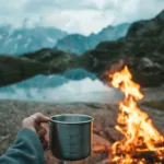 camping, drinking warm coffee tea from portable car kettle